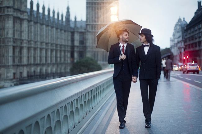 Hai người đàn ông nắm chặt tay nhau, trao cho nhau cái nhìn tình tứ trên con đường của thành phố Luân Đôn.
