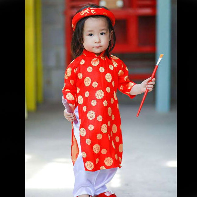 Bé Cat xúng xính trong áo dài đỏ truyền thống trong một bộ ảnh thời trang chụp Tết 2014. 
