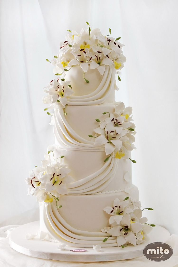 Một mẫu bánh cưới được trang trí với nhiều kiểu hoa mềm mại, tinh khôi.
