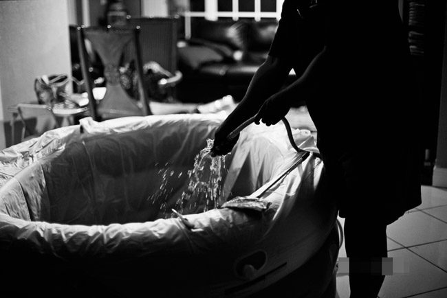Sau khi được khám, nữ hộ sinh thông báo cô sẽ sắp sinh nở. Lúc này, người chồng bắt đầu công tác chuẩn bị bồn nước ấm cũng như những dụng cụ cần thiết khác cho ca sinh.
