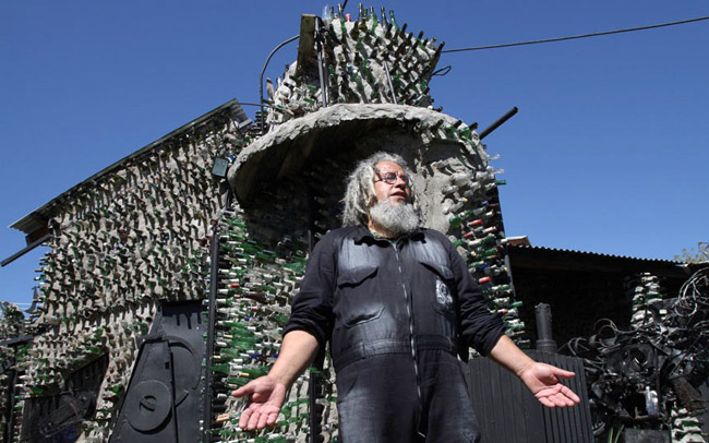 Artist Tito Ingenieri đứng trước ngôi nhà được xây nên bởi hơn 30.000 chiếc vỏ chai ở Quilmes, Argentina.
