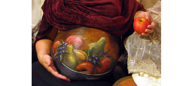 Một đĩa trái cây được trang trí trên bụng mẹ bầu.
