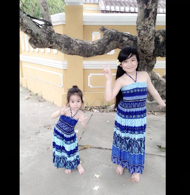 Hai cô bé điệu đà trong bộ váy xanh khi đi biển.
