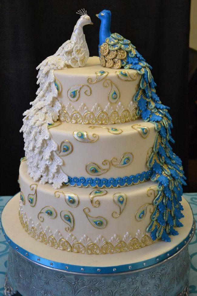 Đôi công được trang trí trên bánh tượng trưng cho cô dâu và chú rể. Chiếc bánh cưới trở nên mềm mại, sinh động hơn nhờ hình ảnh của đôi chim này.
