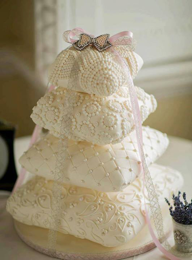 Một chiếc bánh cưới với màu trắng tinh khiết được thiết kế theo hình chiếc khối thể hiện cuộc sống ấm êm và hạnh phúc của cô dâu, chú rể.
