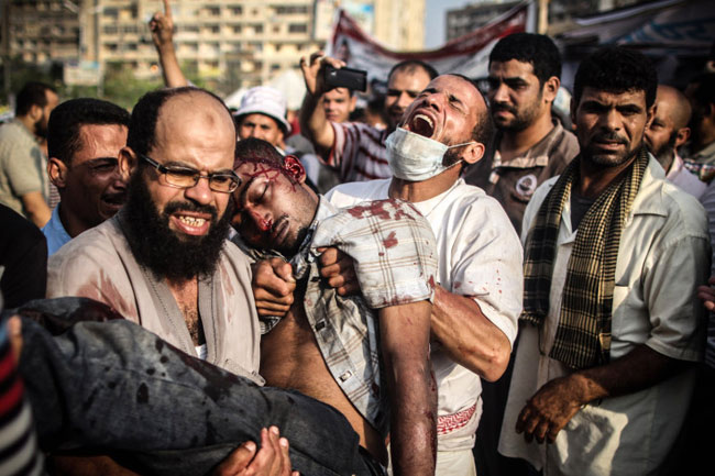 Người đàn ông trung niên Ai Cập bế một thanh niên bị thương nặng trong cuộc đụng độ với cảnh sát tại Cairo. Các lực lượng an ninh Ai Cập đã tấn công những người biểu tình ủng hộ cựu Tổng thống bị lật đổ Morsi ngày 27/7.
