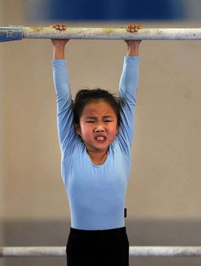 Hình ảnh một cô bé còn nhỏ tuổi đang phải tập luyện tích cực tại trường thể thao. Ngay từ khi còn nhỏ, những đứa trẻ này đã khuyến khích tập luyện để giành huy chương vàng ở Olympic

