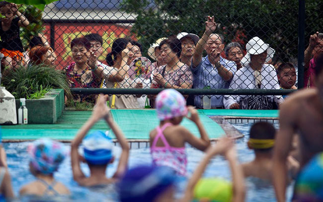 Cảnh bố mẹ đứng xem các con tham gia buổi tập bơi
