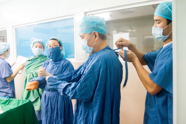 Bác sĩ mổ đẻ chính Phan Văn Quý đang mặc áo và đi gang tay vô khuẩn để sẵn sàng cho ca mổ đẻ diễn ra trong vài phút tới.
