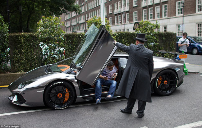 Nhân viên phục vụ giúp một thiếu gia Kuwaiti ra khỏi chiếc siêu xe Lamborghini Aventor tại khu phố nhà giàu Knightsbridge ở London.
