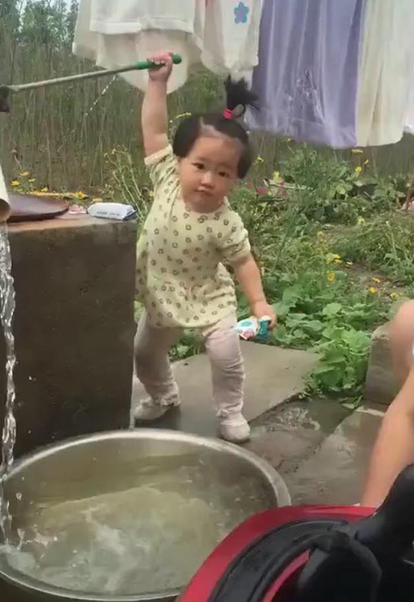 Đánh đu người bơm nước cho mẹ giặt quần áo, bé gái khiến cư dân mạng thích thú - 1