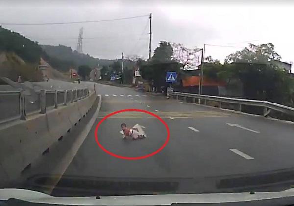 Hãi hùng em bé vài tháng tuổi bò lồm ngồm ngoài đường quốc lộ, ngay trước đầu xe tải - 1