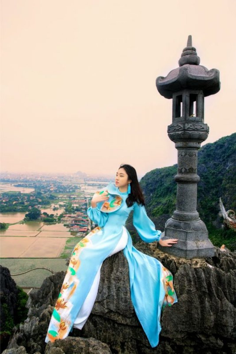Cô gái diện áo dài, tạo dáng trên đỉnh Ngọa Long của Hang Múa.
