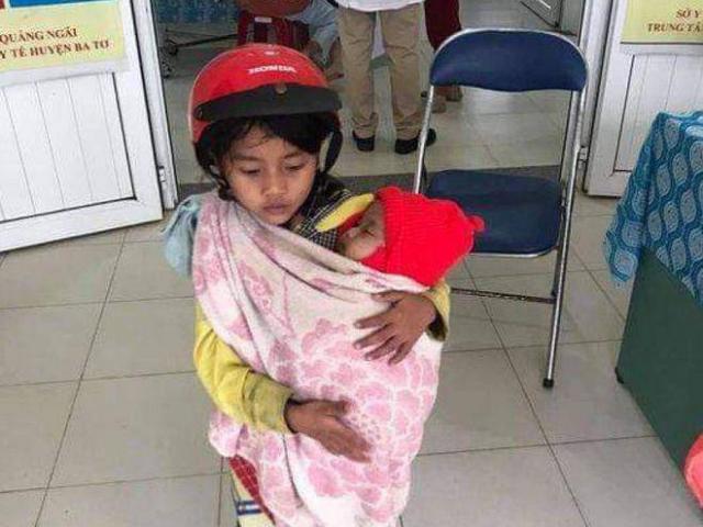 Cảm động bé gái 7 tuổi đội mũ bảo hiểm bế em đi tiêm phòng