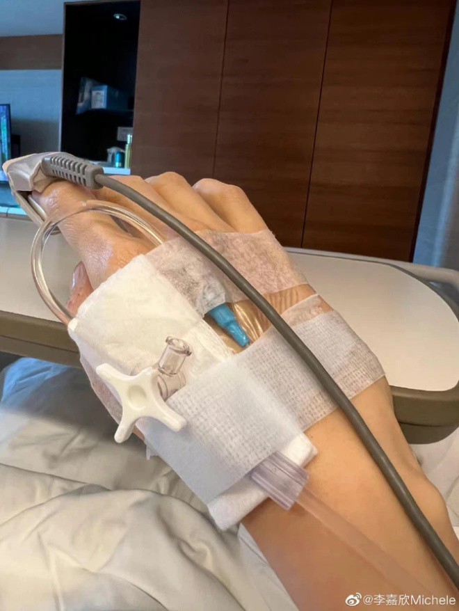 Tay cô chằng chịt băng dán và kim tiêm.