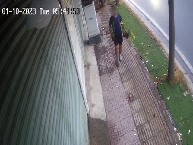 Một người đàn ông vô tư bê chậu cây của nhà dân trên đường