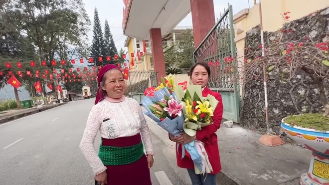Thị Vư và con gái Thị Mỉ ôm bó hoa đứng chờ người trong nhà.