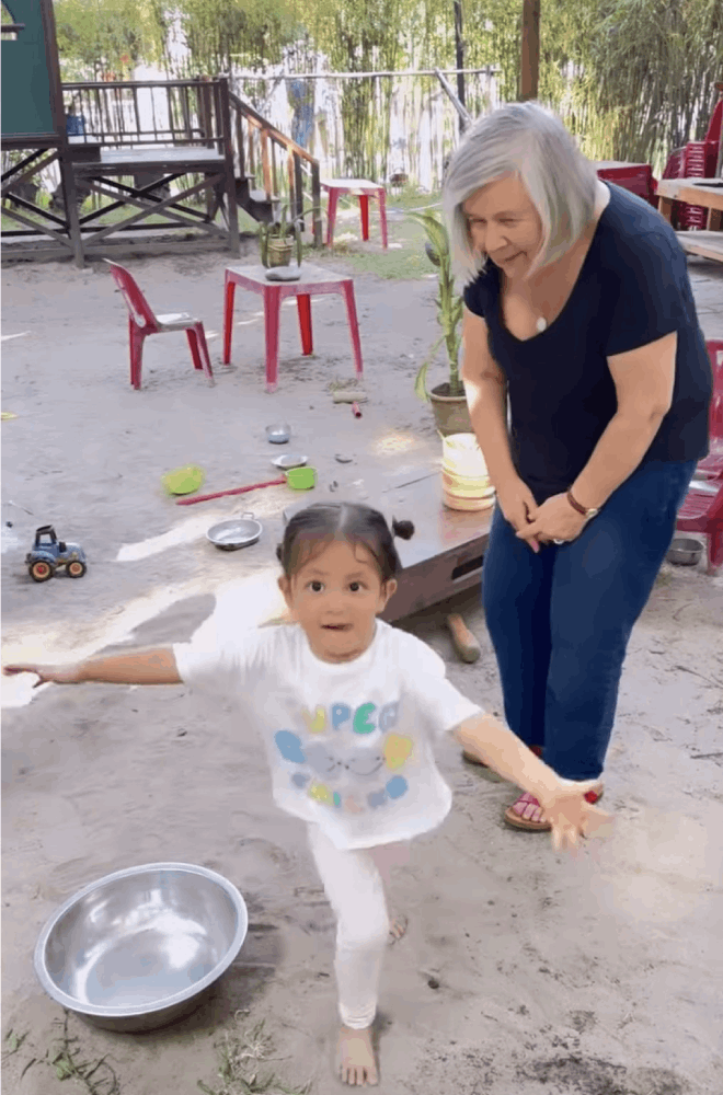 Không chào bà, cô bé bỏ chạy về phía mẹ đòi ôm.