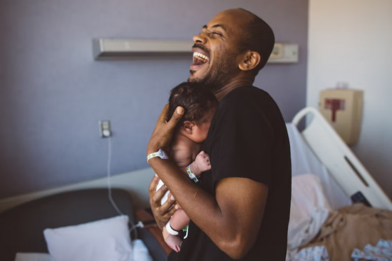 Người cha nở nụ cười tươi hết cỡ khi bế con yêu trên tay. Niềm hạnh phúc ngập tràn lan tỏa.