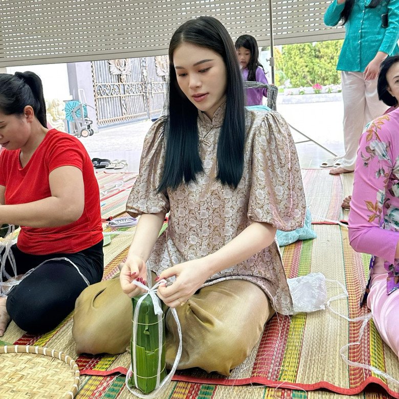 Linh Rin diện mẫu bà ba ngồi gói bánh chưng với gia đình. Trang phục kín cổng cao tường chẳng thể làm giảm bớt đi nét quyến rũ của cô. 