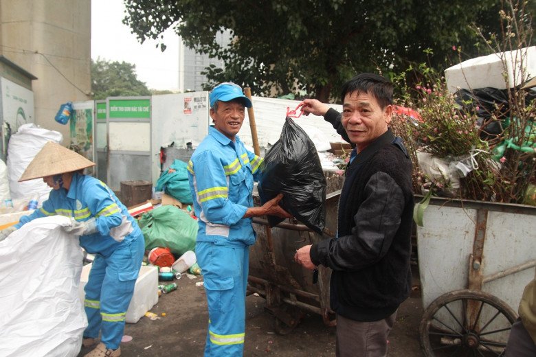 Ông Chiến vui vẻ nhận túi rác thải (chai, lon) đã được phân loại từ người dân. 