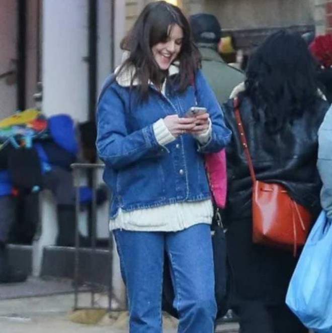 Suri cười tươi khi nhìn vào điện thoại.