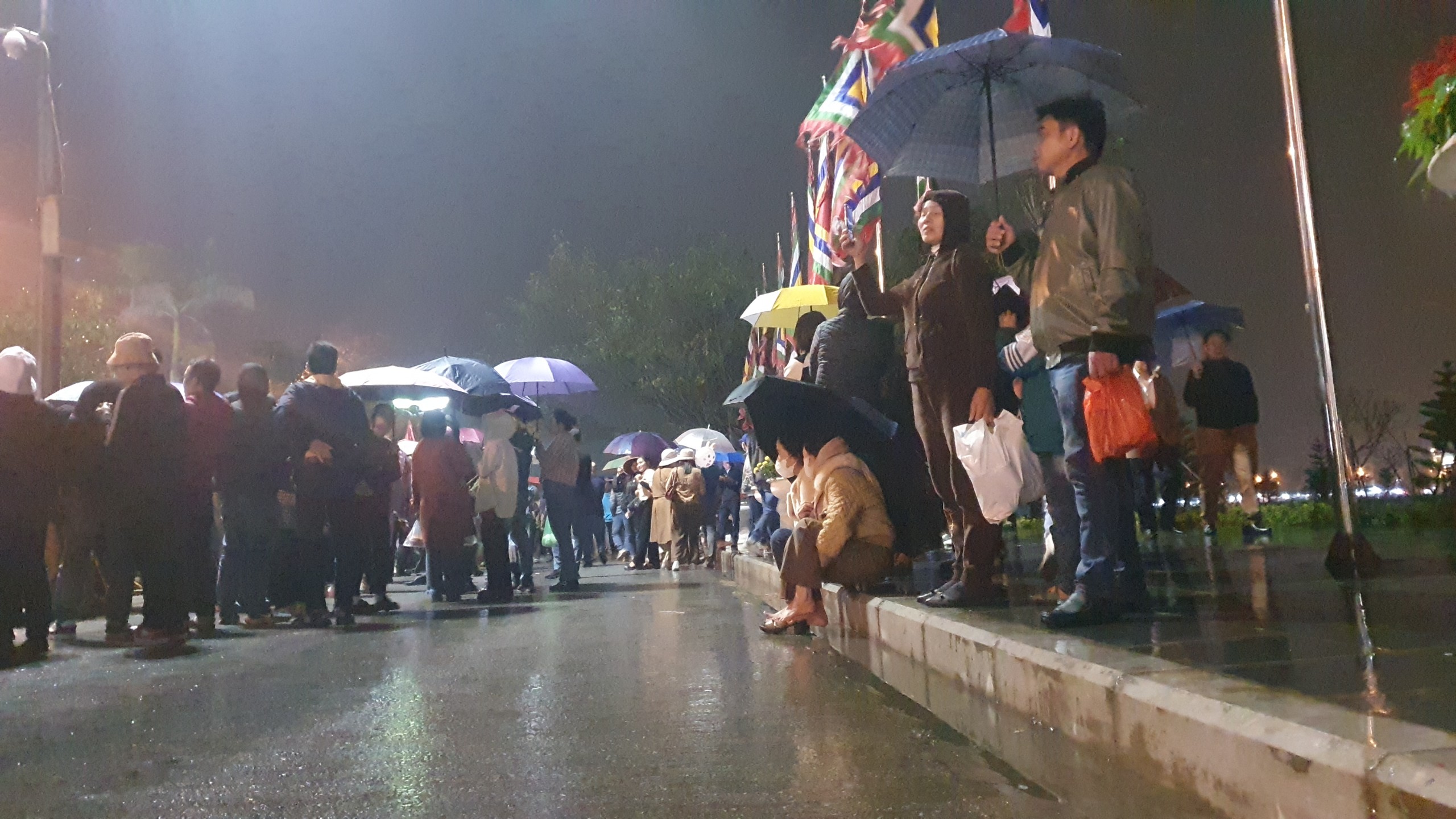 Càng về khuya số lượng người dân đến đền Trần càng đông lên. Nhiều người đứng lâu mỏi chân ngồi trên vỉa hè trước cửa đền.