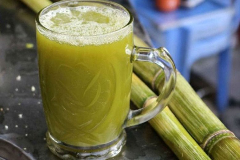 A woman holding a glass of sugarcane juice, showcasing its beauty benefits