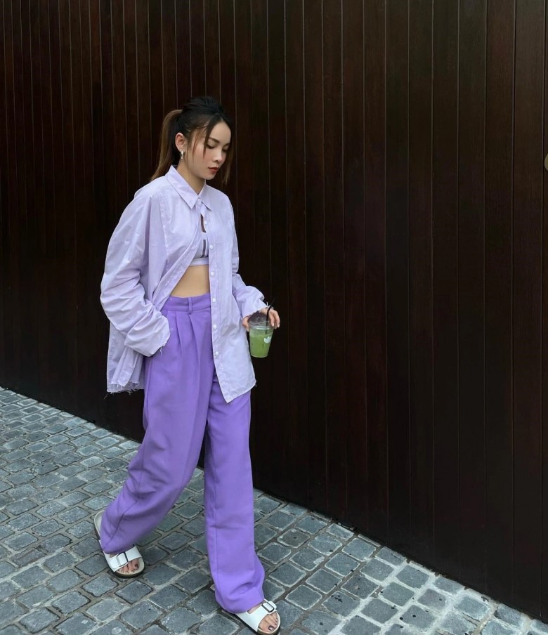 Ca sĩ Yến Trang năng động trong trang phục đầy màu sắc cùng áo sơ mi cài nút hờ và quần ống rộng màu tím pastel.