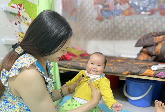 Một nữ công nhân đang tập cho con 5 tháng tuổi ăn dặm, ti bình trước khi quay lại đi làm, trong căn phòng trọ ở Đông Anh, Hà Nội, tháng 3/2023. Ảnh: Phan Dương