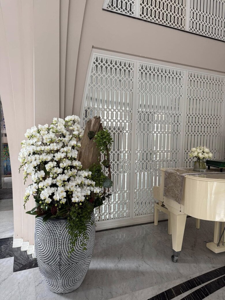 Cây đàn piano trắng được đặt gần cửa ra vào. Hệ thống cửa hoa văn phía sau giúp phản chiếu ánh sáng, làm căn phòng thêm phần rộng rãi và sáng sủa.
