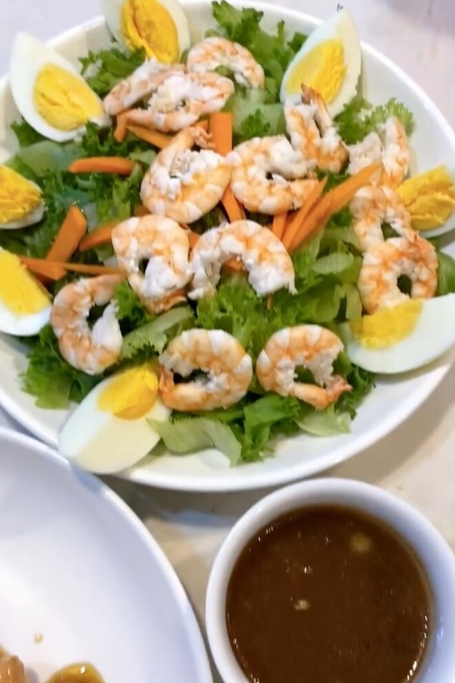 Đĩa salad tôm trứng rực rỡ màu sắc, kết hợp giữa vị tươi ngon của rau xanh, độ ngọt của tôm và béo bùi của trứng, ăn kèm nước sốt.