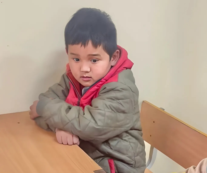 Cậu bé ngồi trong góc bàn nhìn các bạn