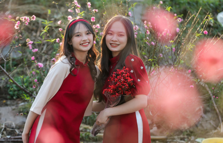 Hai bạn trẻ diện áo dài chụp ảnh cùng với hoa đào Nhật Tân. (Ảnh: Ngô Nhung)