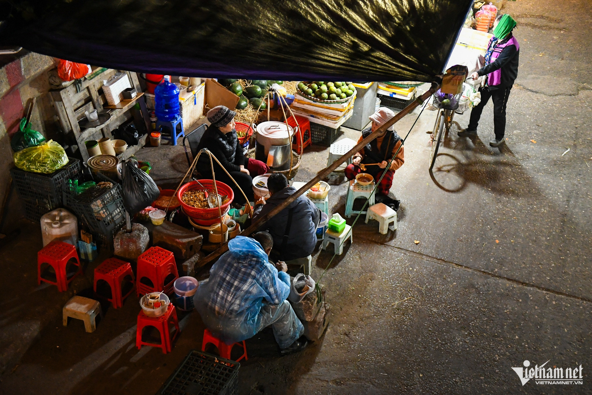 Khu vực chợ Long Biên vẫn nhộn nhịp trong đêm. Nhiều người lao động phải mặc thêm áo mưa để chống lại giá rét.