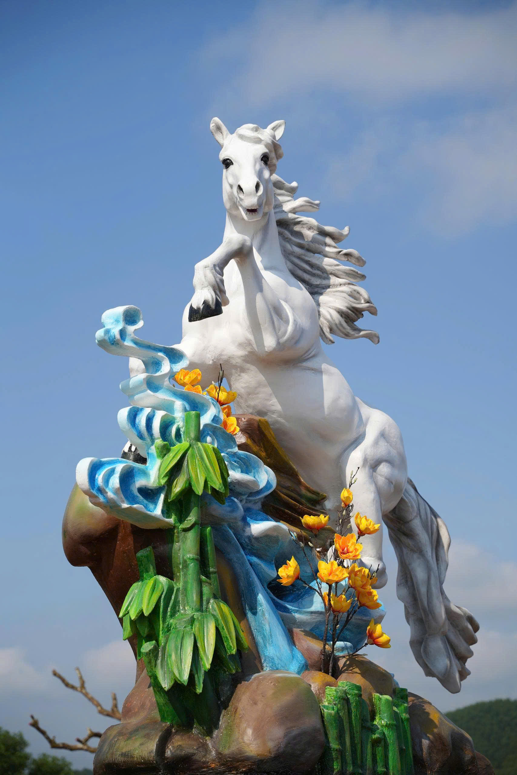 Dưới chân tượng là khóm tre và dòng thác xanh, vừa làm nổi bật linh vật, vừa gợi nhắc đến sự kiên trung, bền bỉ.