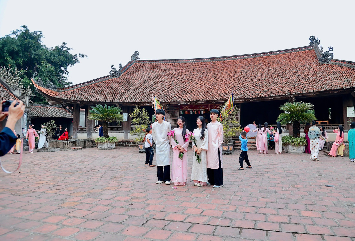 Những ngày cuối năm, làng cổ Đường Lâm khoác lên mình vẻ nhộn nhịp khác thường. Trên những con ngõ lát gạch, dưới mái tường đá ong nhuốm màu thời gian, từng nhóm bạn trẻ trong tà áo dài thướt tha say mê thả dáng, chụp ảnh. Ai cũng muốn ghi lại không khí Tết sớm giữa không gian cổ kính hiếm hoi còn sót lại của vùng trung du Bắc Bộ.