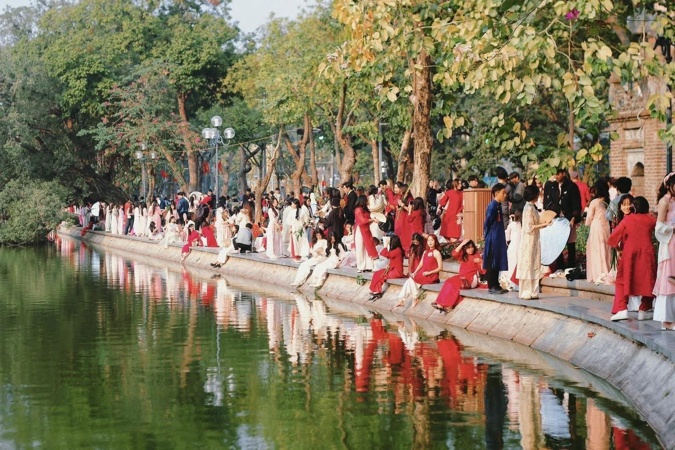 Từ sáng đến chiều, quanh các địa điểm quen thuộc như Tháp Rùa, cầu Thê Húc, đền Ngọc Sơn hay phố Đinh Tiên Hoàng, hình ảnh những cô gái trẻ diện áo dài đủ màu sắc xuất hiện liên tục. Áo dài đỏ, hồng, trắng hoặc họa tiết hoa được ưu tiên lựa chọn, gợi không khí Tết trong những ngày cuối năm.