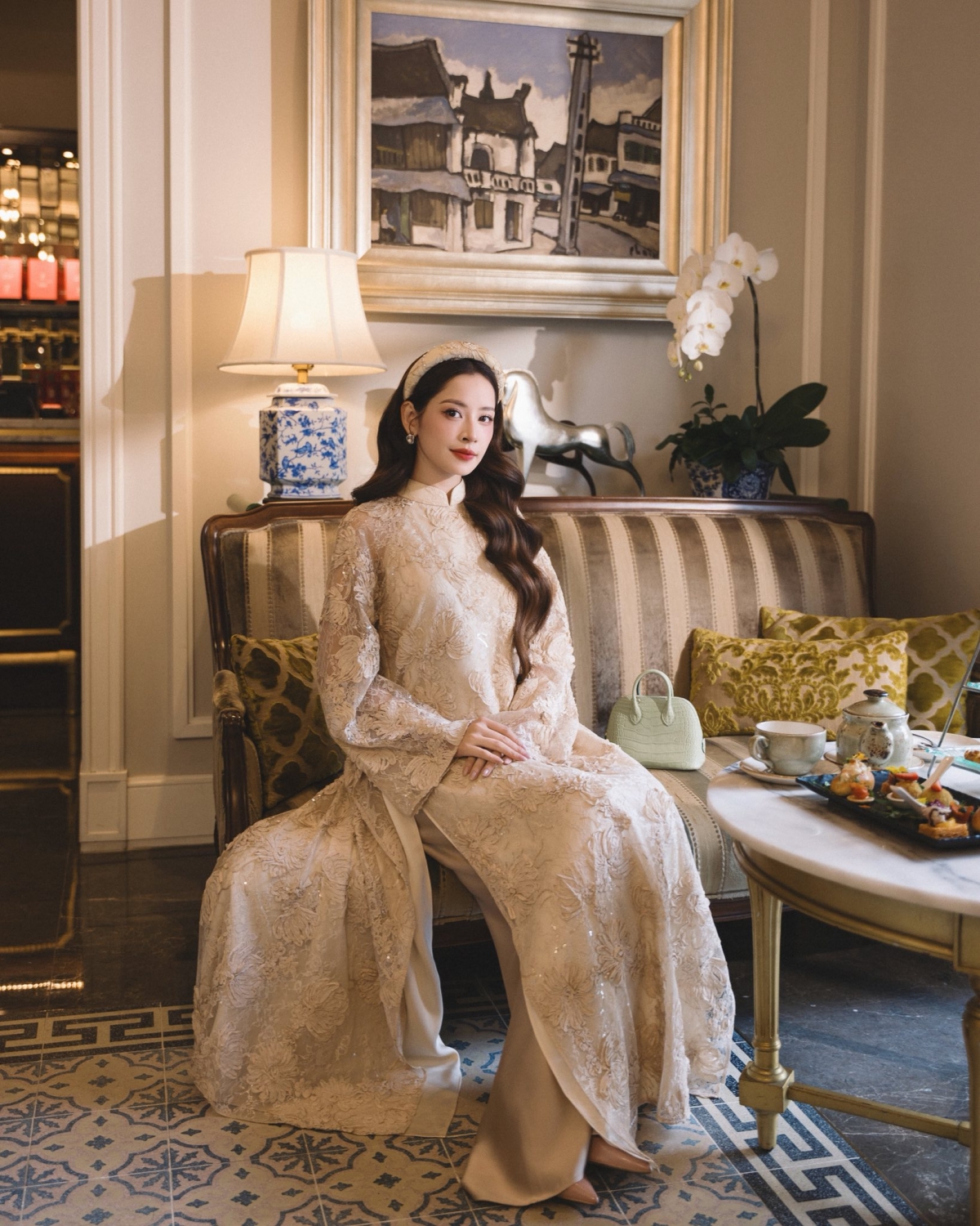 Chi Pu lựa chọn áo dài ren thêu, kết hợp giữa nền ren mềm mại và họa tiết thêu thủ công cầu kỳ. Thiết kế mang đến hình ảnh nữ tính, sang trọng, phù hợp với không khí lễ hội truyền thống nhưng không kém phần thời thượng.