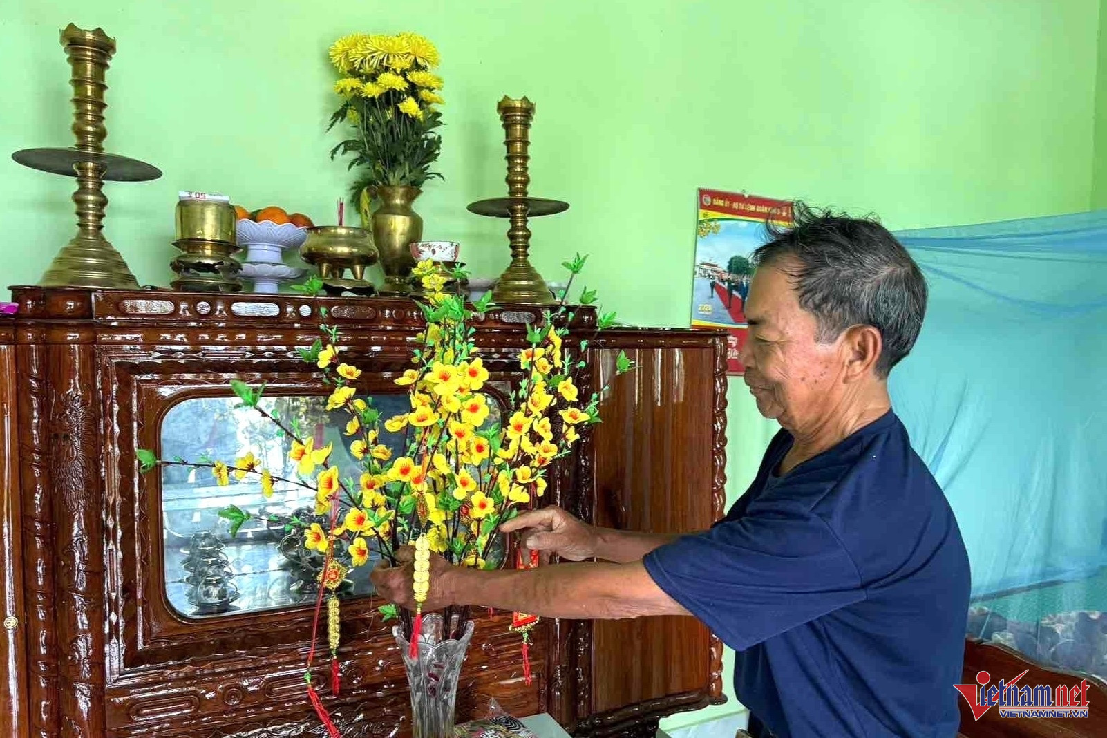 Ông Trần Văn Khánh (76 tuổi, trú thôn Phú Hữu) cắm hoa chuẩn bị đón Tết trong ngôi nhà mới khang trang của Chiến dịch Quang Trung. Ảnh: Hải Dương