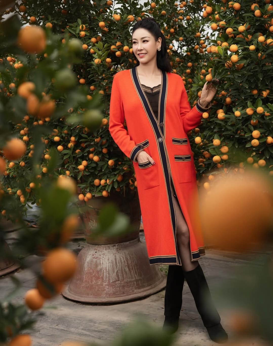 Hoa hậu phối mẫu áo khoác trăm triệu đồng cùng áo hai dây ren và chân váy ngắn, đi cùng boots cao đến bắp chân.