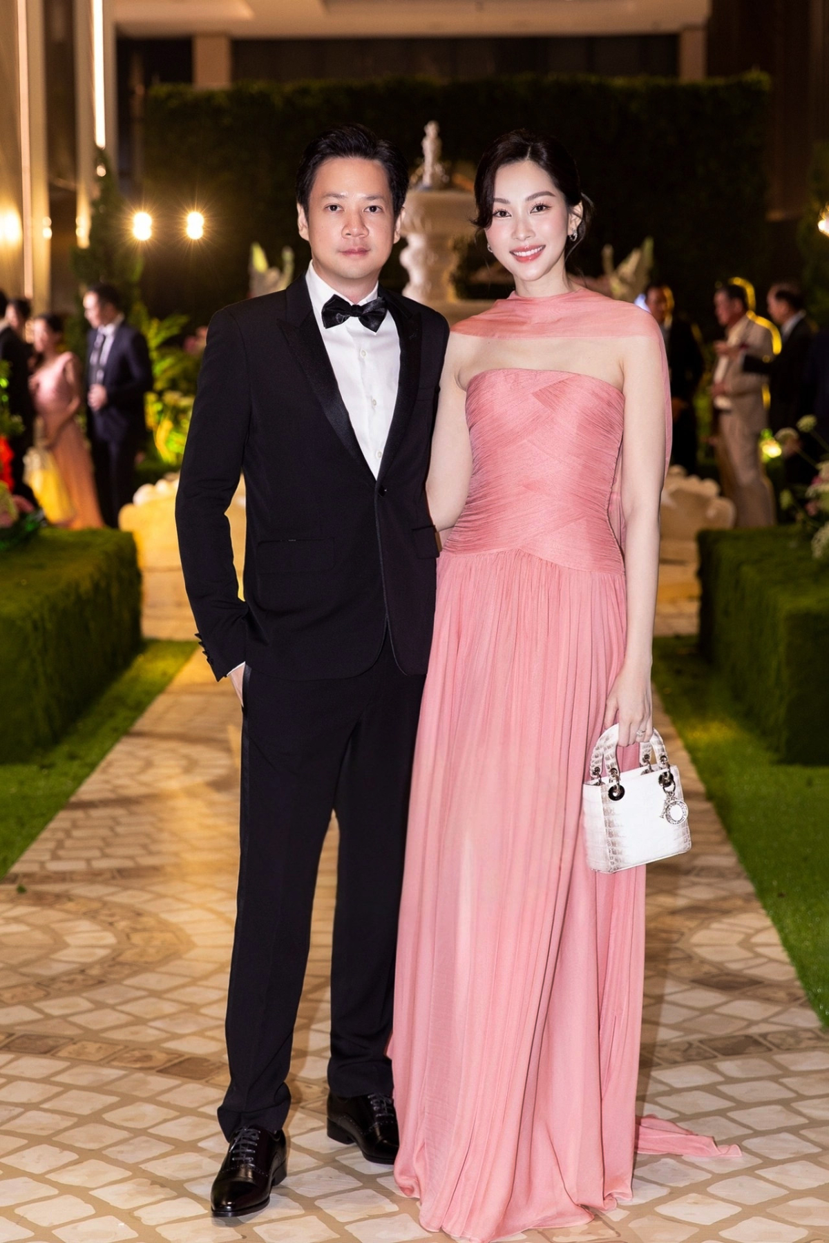 Vợ doanh nhân Trung Tín còn bổ sung mẫu túi da cá sấu bạch tạng từ nhà mốt Dior vào bộ sưu tập hàng hiệu xa xỉ. Cô kết hợp nó với đầm hồng xếp nếp nữ tính khi dự đám cưới rich kid Tiên Nguyễn tháng 12/2025.