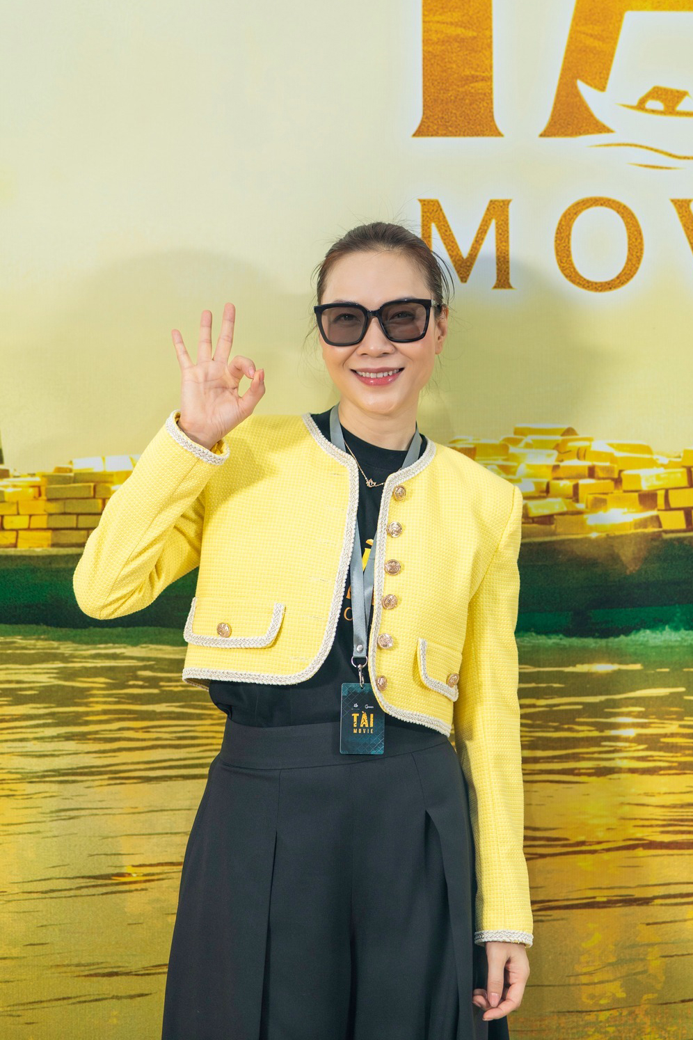 Mỹ Tâm mặc áo khoác màu vàng đính khuy kim loại nổi bật trong một hoạt động của phim Tài.