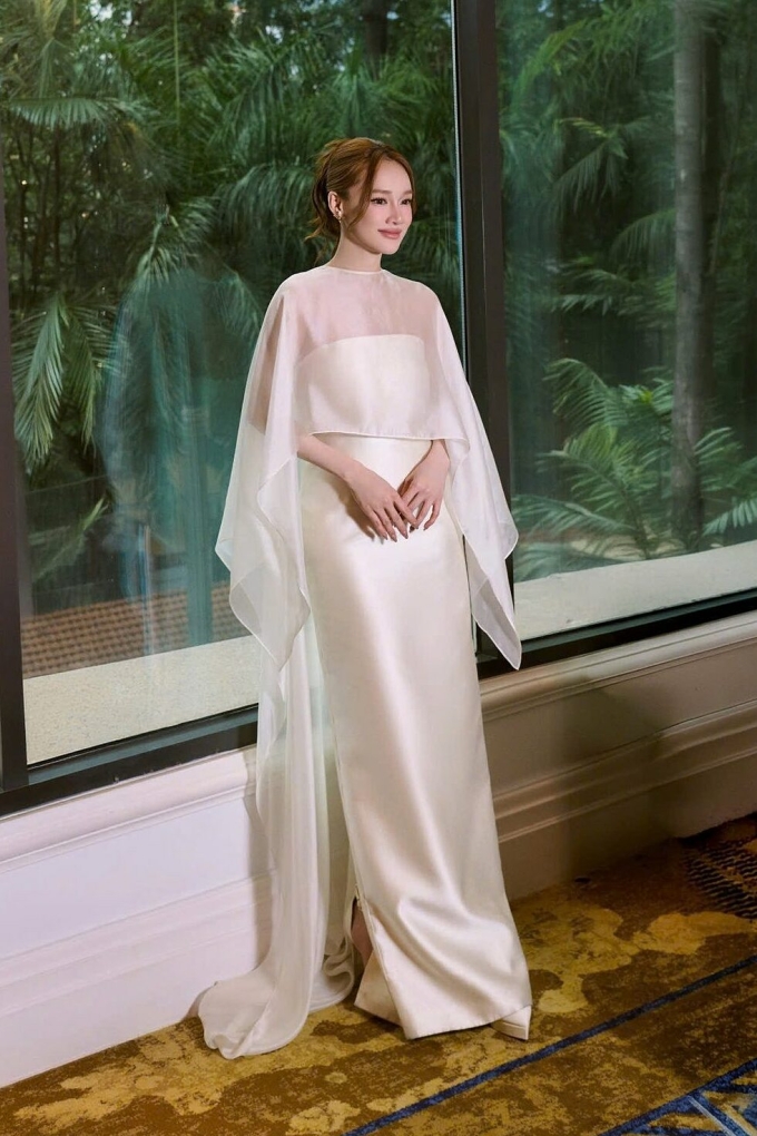 Nhã Phương diện đầm satin phối voan trắng kem đi sự kiện.