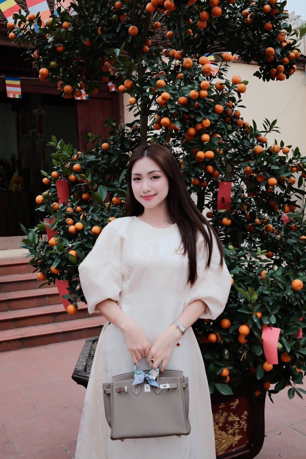 Dịp Tết năm nay, ca sĩ chọn nhiều kiểu áo dài mặc đi lễ, du xuân cùng gia đình và bạn thân. Người đẹp 31 tuổi phối áo cách tân cùng túi Birkin của Hermes hàng trăm triệu đồng, vòng tay cỏ bốn lá nổi tiếng đắt đỏ của Van Cleef amp; Arpels.