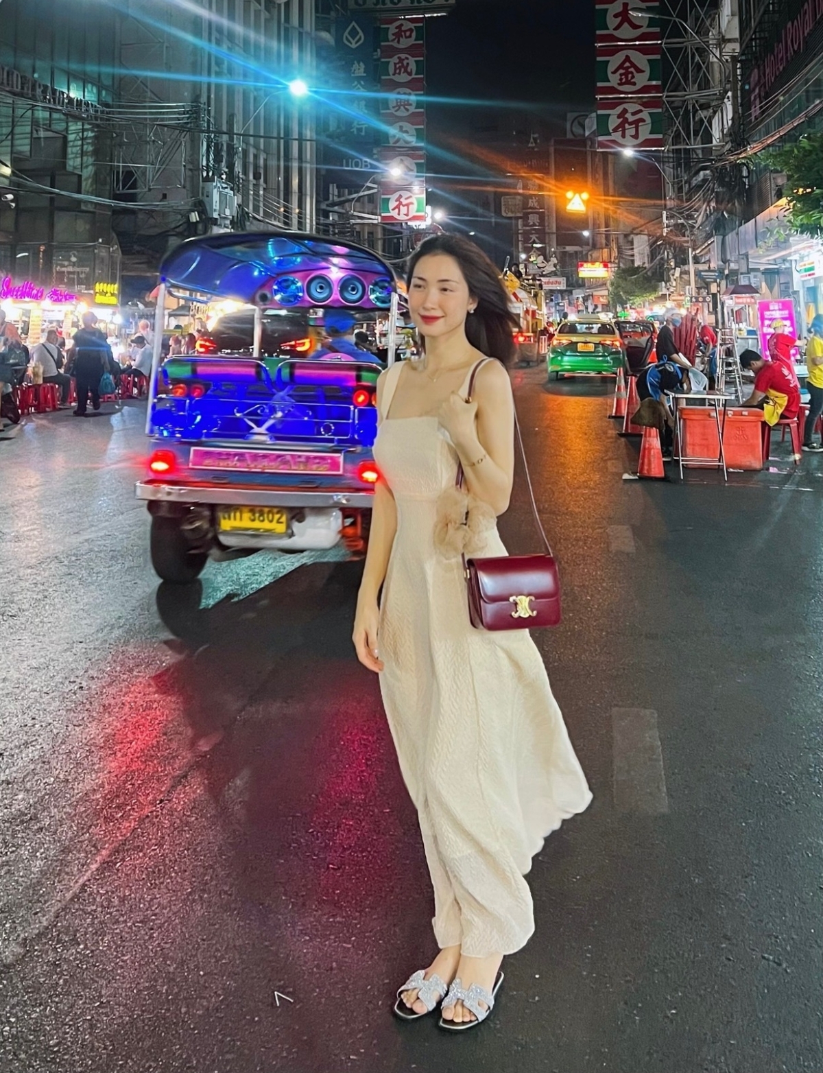 Trong một chuyến du lịch Thái Lan, cô mang dép Hermes và túi Celine, kết hợp đầm midi màu kem.
