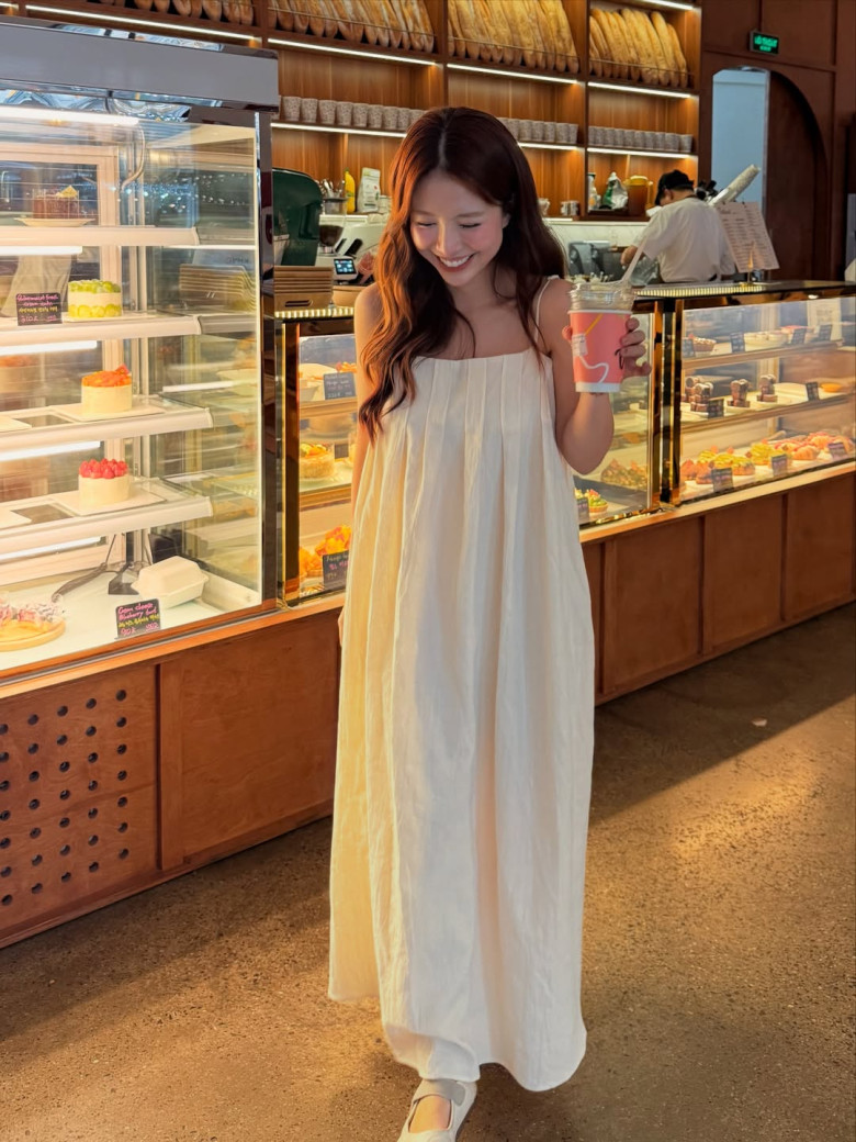 Chiếc váy maxi trắng trơn mang tinh thần tối giản lên ngôi, nhưng chính sự tinh giản ấy lại làm nổi bật thần thái thanh thoát của Mẫn Tiên. Chất liệu rũ nhẹ theo từng bước chân, tạo nên chuyển động mềm mại và đầy nữ tính. Không cần chi tiết cầu kỳ, chỉ một đôi giày bệt cũng đủ hoàn thiện hình ảnh một quý cô hiện đại.