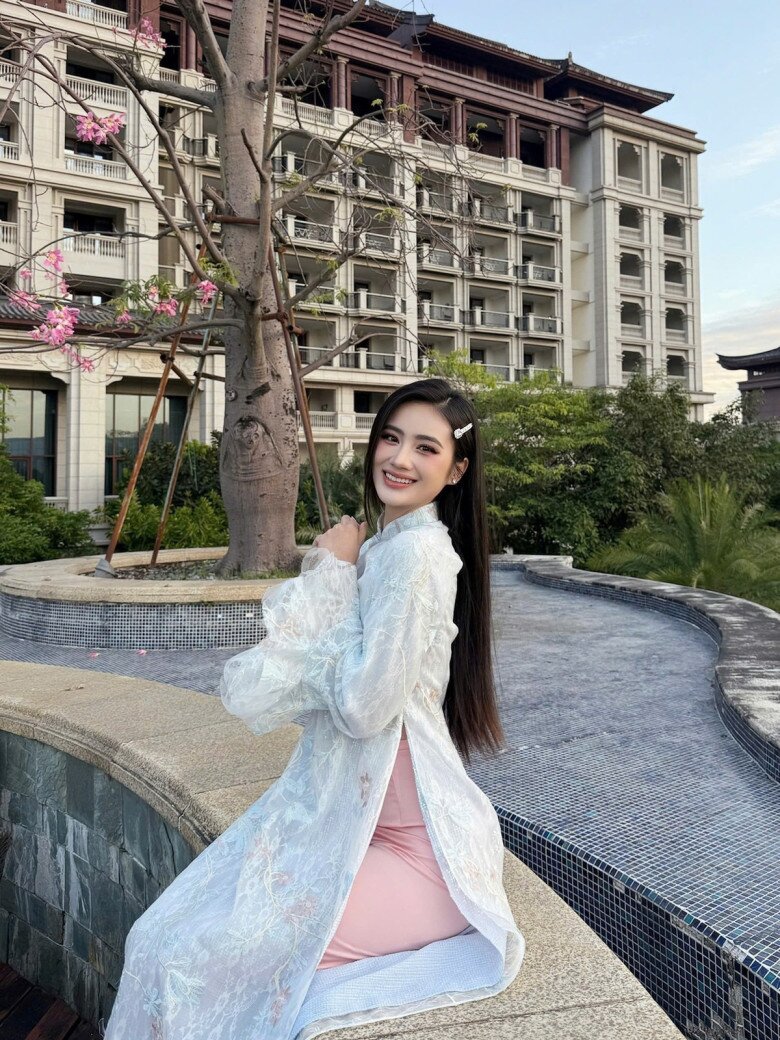 Mẫu áo dài trắng của hoa hậu Ý Nhi được xử lý trên nền ren mỏng, xuyên thấu vừa đủ để tạo cảm giác bay bổng nhưng vẫn kín đáo. Phần tay phồng mềm mại mang hơi thở cổ điển, trong khi dáng áo ôm vừa phải lại rất hiện đại, tôn trọn vóc dáng người mặc. 