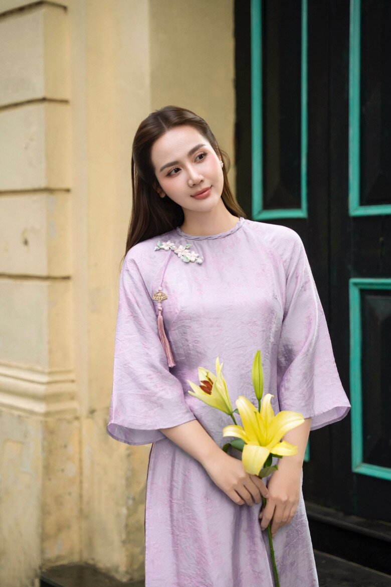 Nữ diễn viên Huyền Lizzie diện mẫu áo dài tím lavender thời thượng được xử lý trên nền lụa nhẹ, kết hợp phụ kiện cài áo và tua rua mềm mại, tạo nên tổng thể ngọt ngào, nữ tính. Thiết kế đơn giản nhưng nền nã, phù hợp với chị em thích sự nhẹ nhàng mà vẫn đủ để tôn dáng.