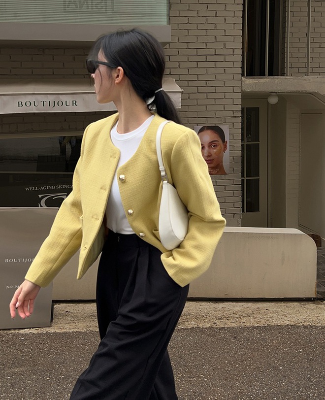 Áo khoác vàng pastel kết hợp cùng quần âu đen tạo nên sự đối lập bắt mắt nhưng tinh tế. Vàng bơ không quá rực, đủ để làm sáng gương mặt và tổng thể. Trắng được thêm vào ở áo trong và túi xách như một lớp đệm trung gian, giúp bảng màu trở nên hài hòa, dễ ứng dụng.